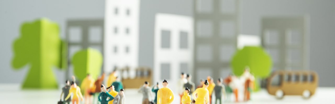 Des silhouettes de personnes en papier se tiennent devant une ville animée.